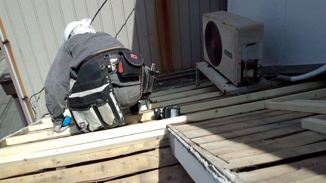 作業員が屋根下地の補強を行っている